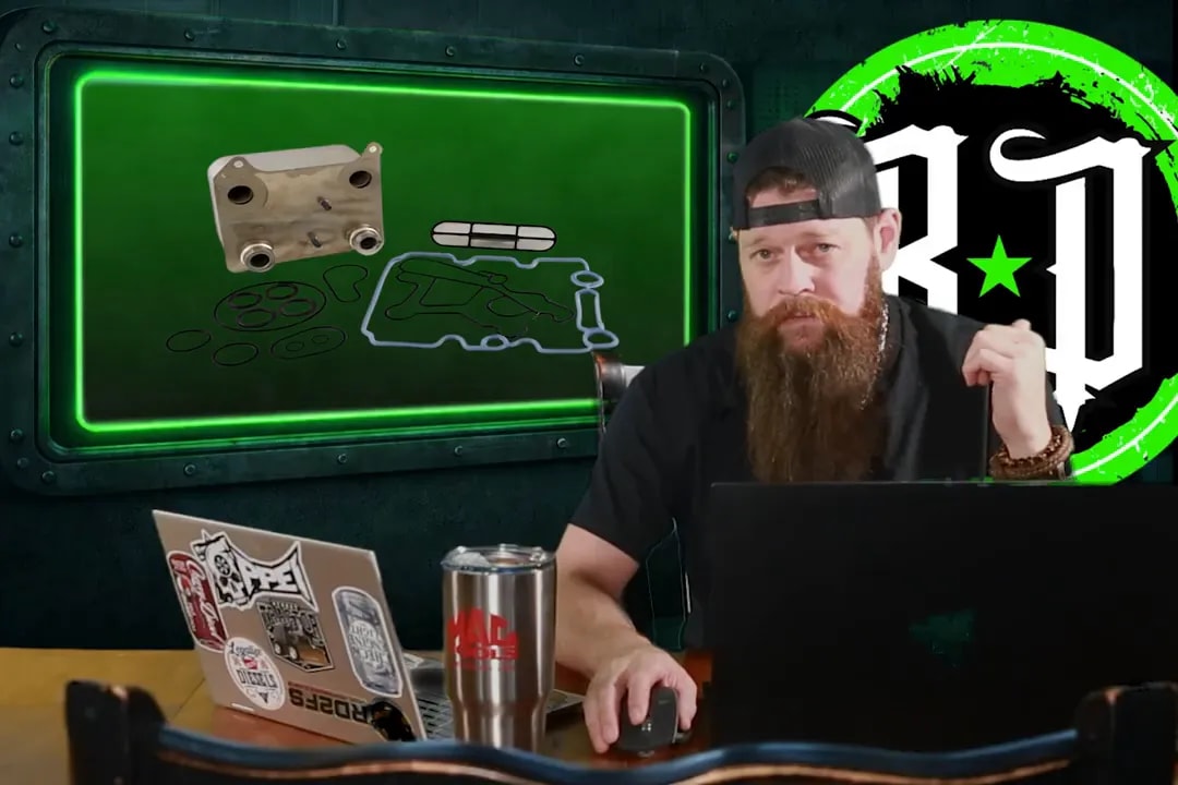 Clear shot of presenter at desk with a display showing an oil cooler and gasket kit components